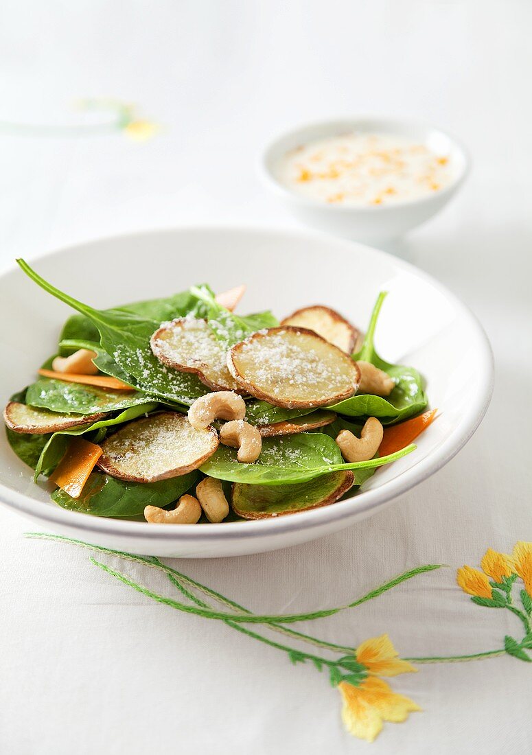 A spinach salad with potatoes and cashew nuts