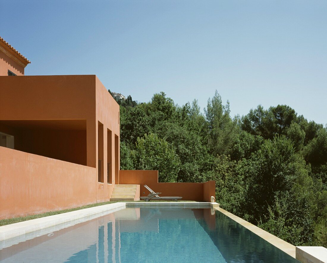 Urlaubsstimmung am Pool vor Mediterraner Haus mit rotbrauner Fassade