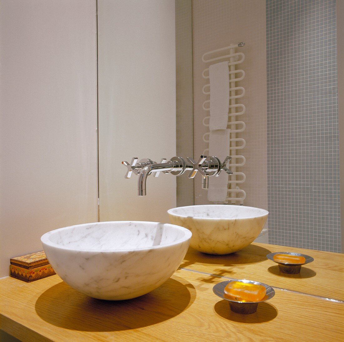 Marble wash basin on a wooden countertop and designer fittings from the mirrored wall
