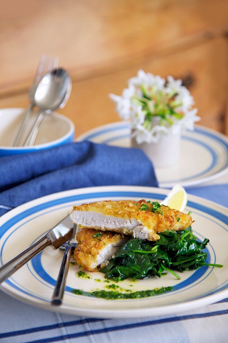 Paniertes Hähnchenschnitzel mit Blattspinat und Zitrone