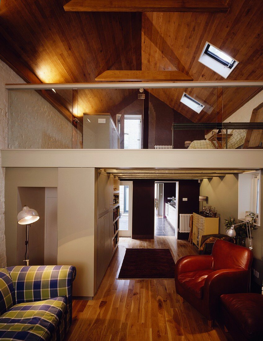 Living room in a converted attic with mezzanine and wood paneling on the ceiling