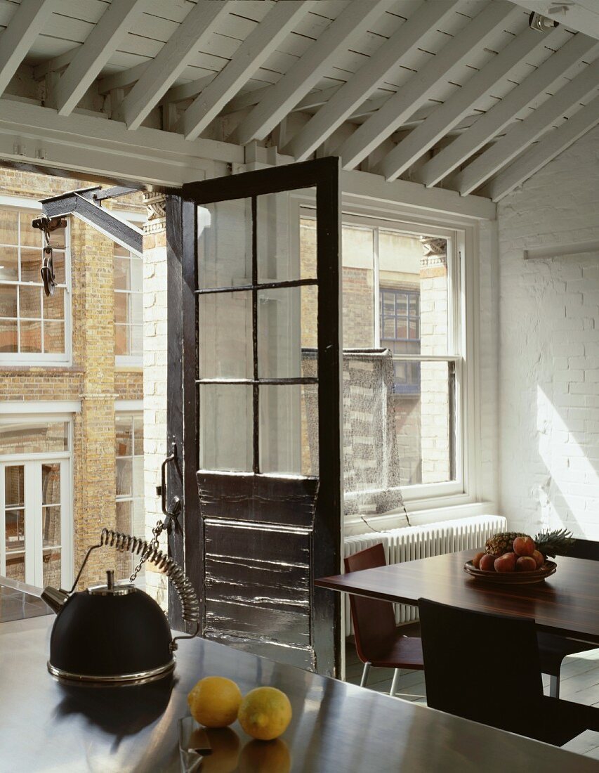 Open balcony door in vintage style in a designer kitchen with white, wooden ceiling