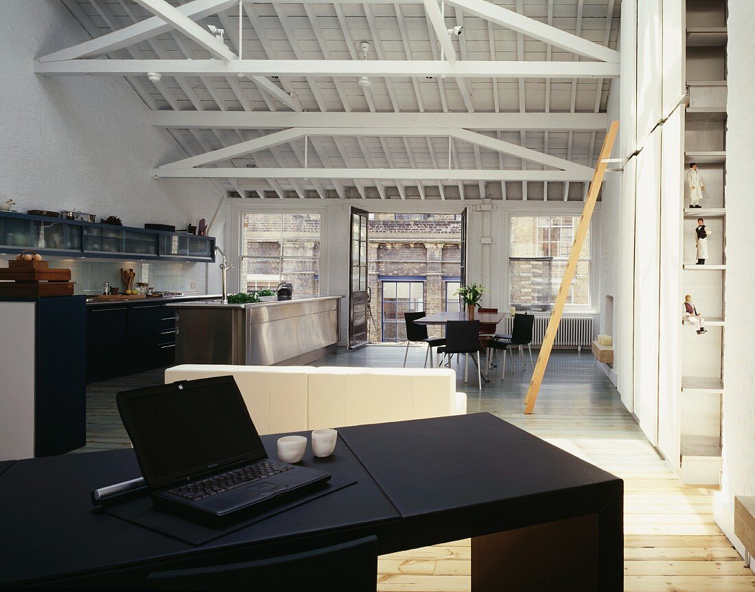 Loft in a former factory building with black writing desk and open kitchen