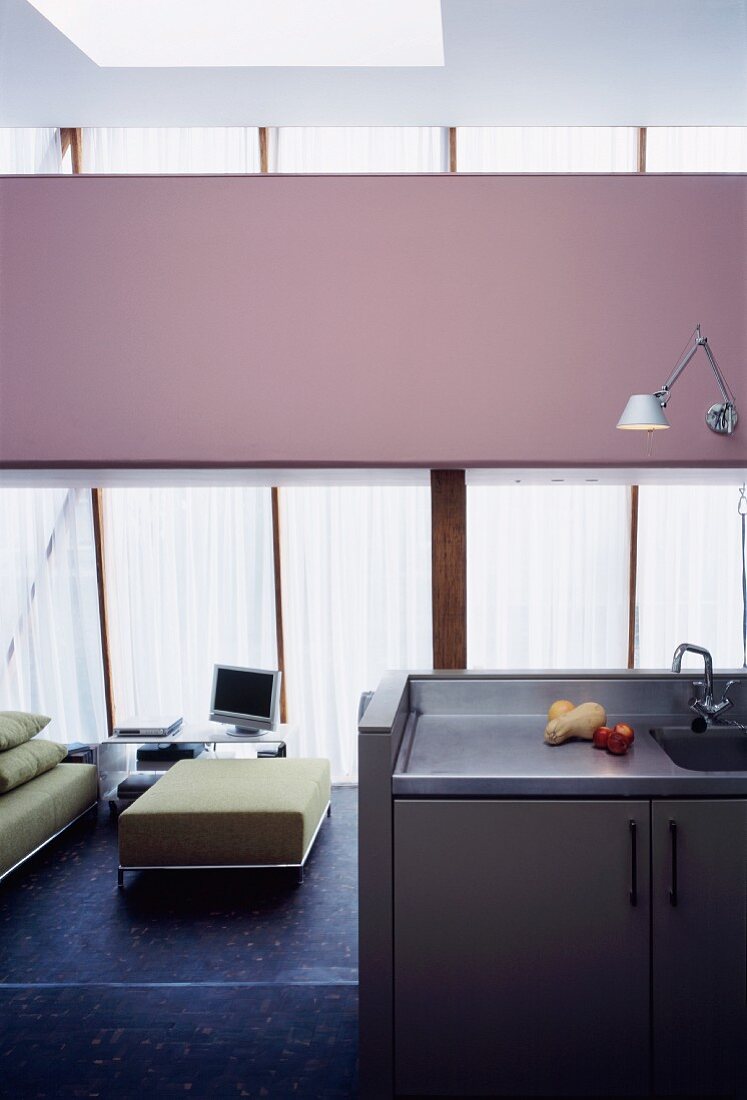 Kitchen detail with sink and view into an open, modern living room at a bright green ottoman