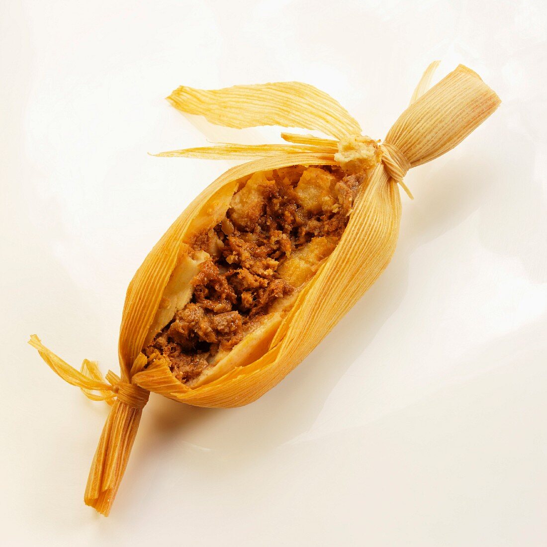 One Meat Filled Tamale Cut Open; White Background