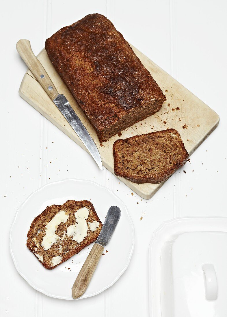 Bananenbrot, angeschnitten auf Holzbrett & Teller