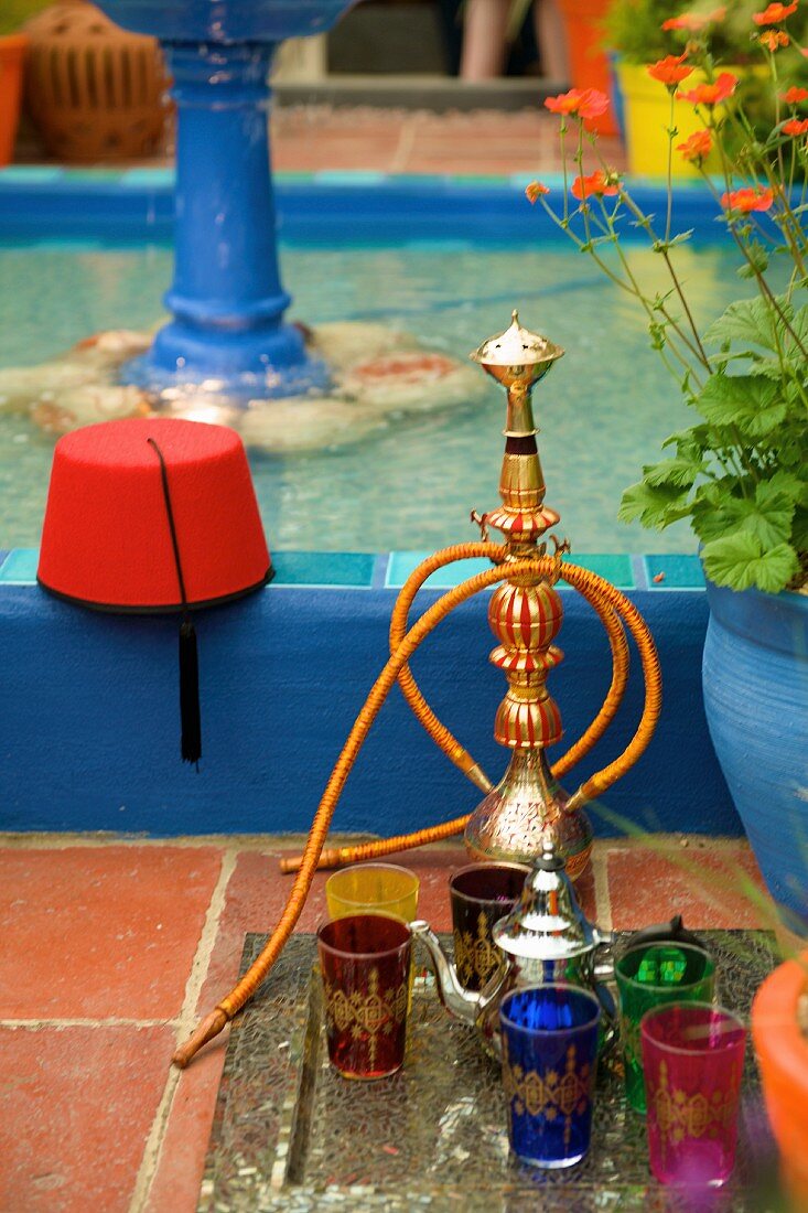 An oriental water pipe and glasses next to a fountain