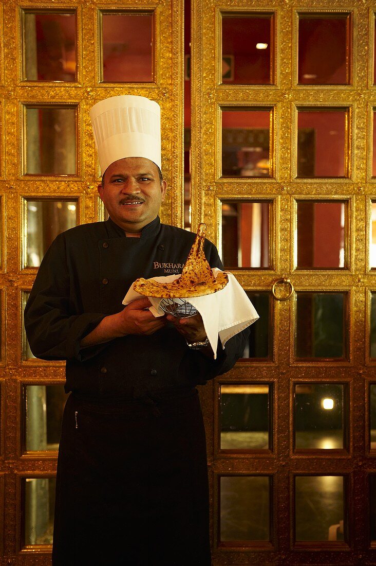 An Indian head chef serving naan bread
