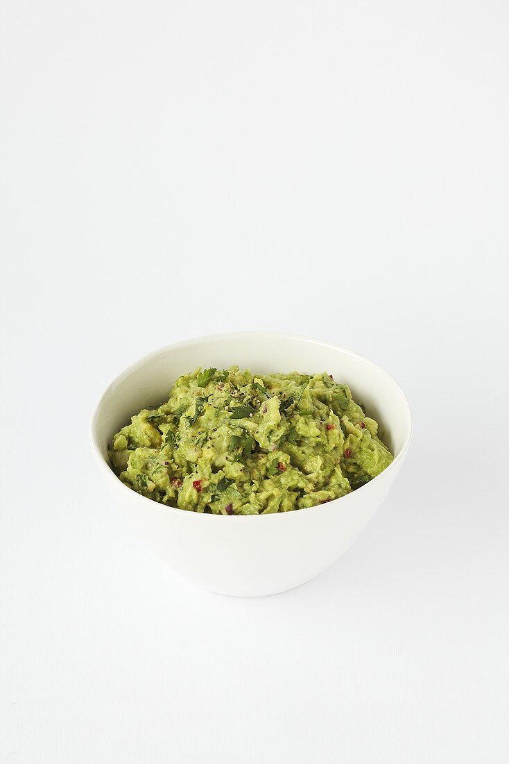 A bowl of guacamole against a white background