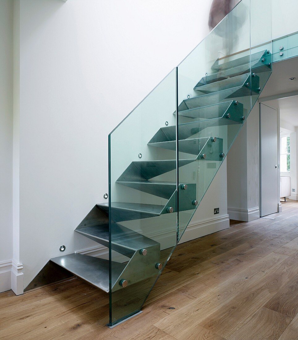 Metal, cubist designer stairs with glass balustrade in purist foyer