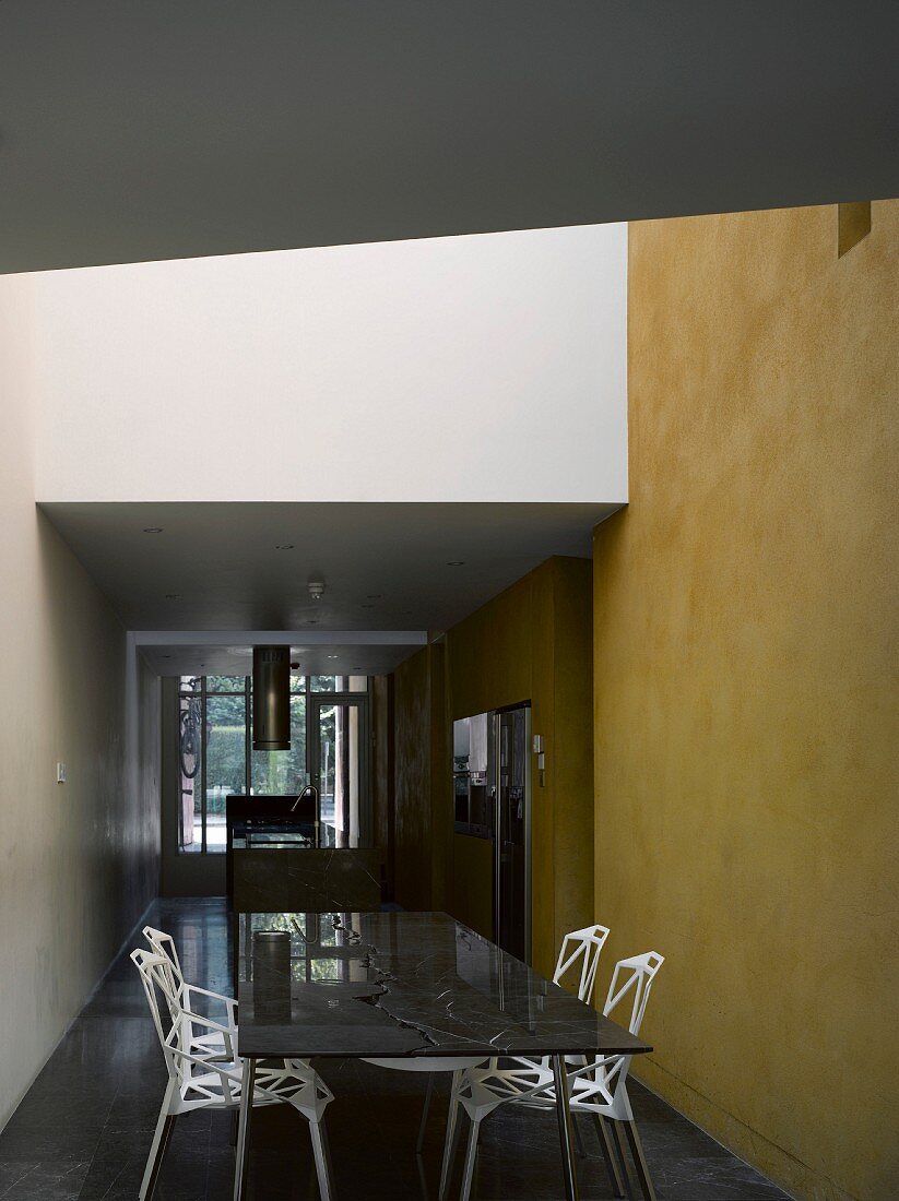 Cool design -- dining table and chairs in designer style in front of a yellow wall in an open lobby
