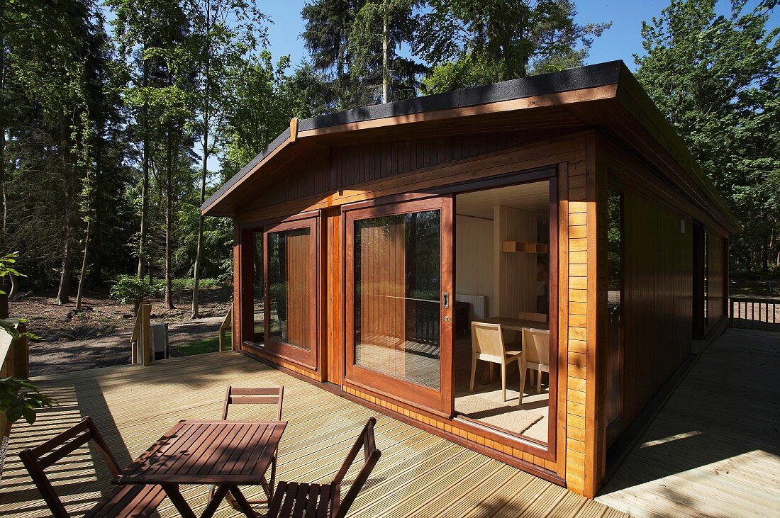 Modernes Wochenendhaus aus Holz mit Tisch und Stühlen auf grosser Terrasse