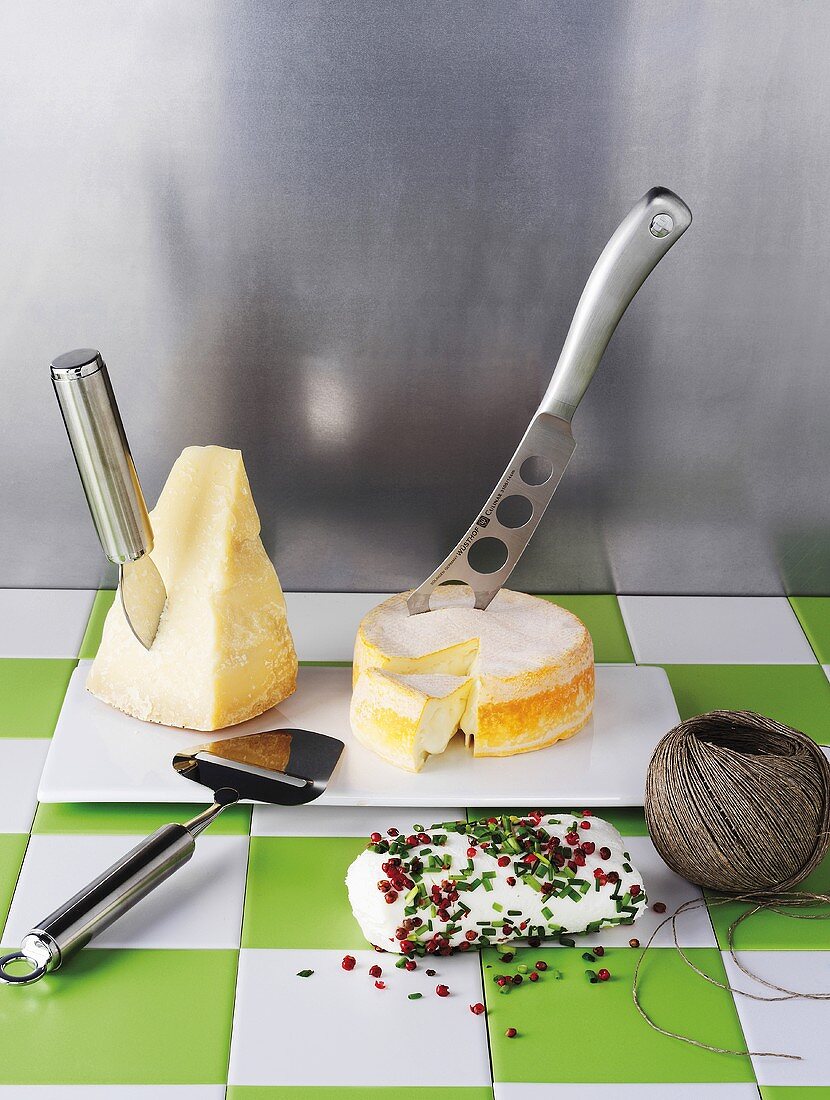 Various sorts of cheese, a cheese knife, a cheese slicer and kitchen twine