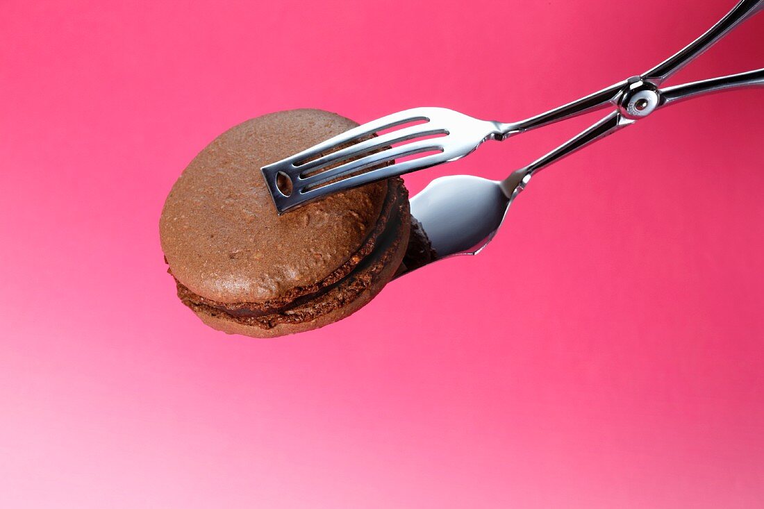 Cake tongs holding a chocolate macaroon