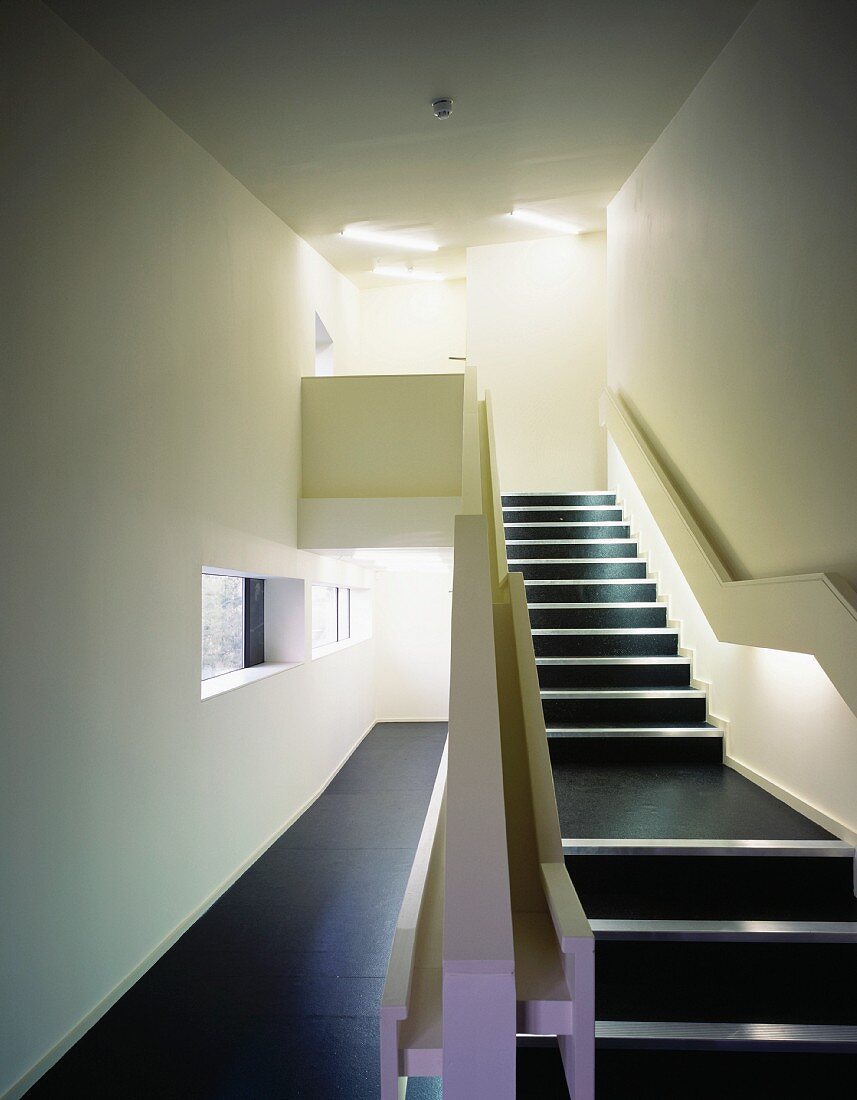 Minimalist stairway with black floor covering in the passage way and on the steps