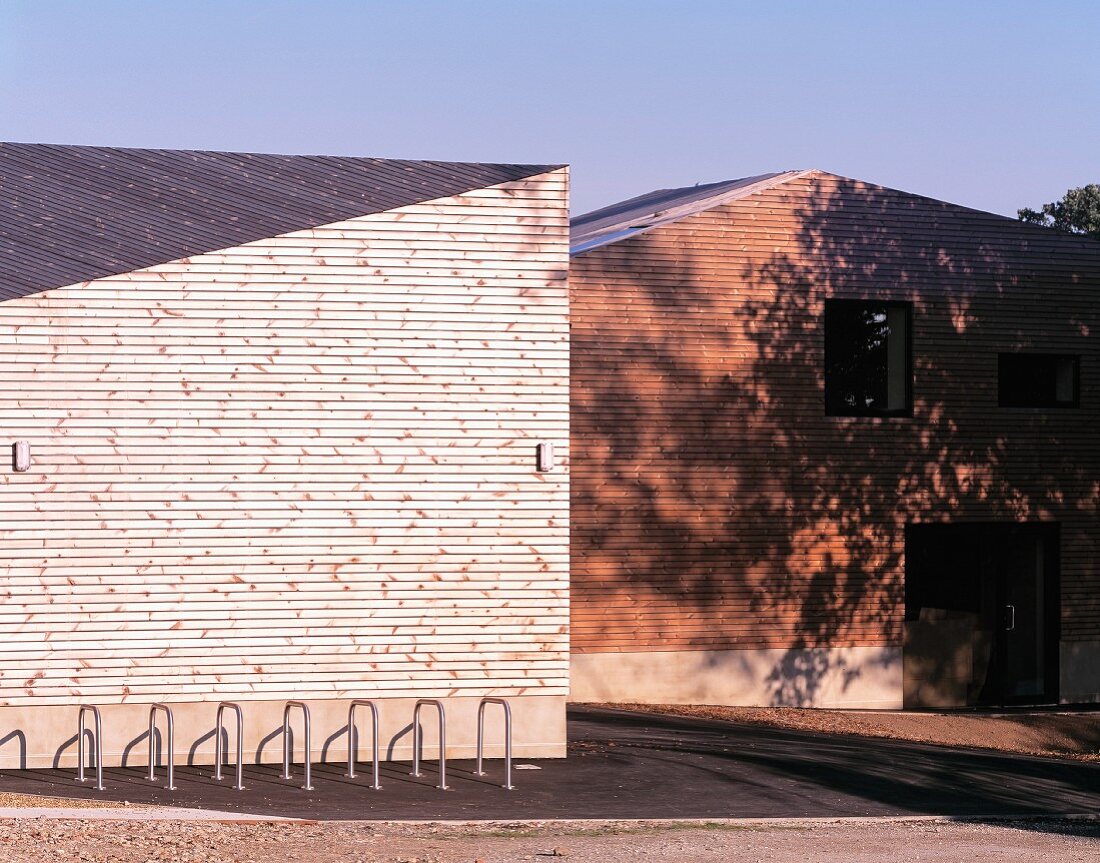 Bike racks in front of a house with a wood clad roof and wall