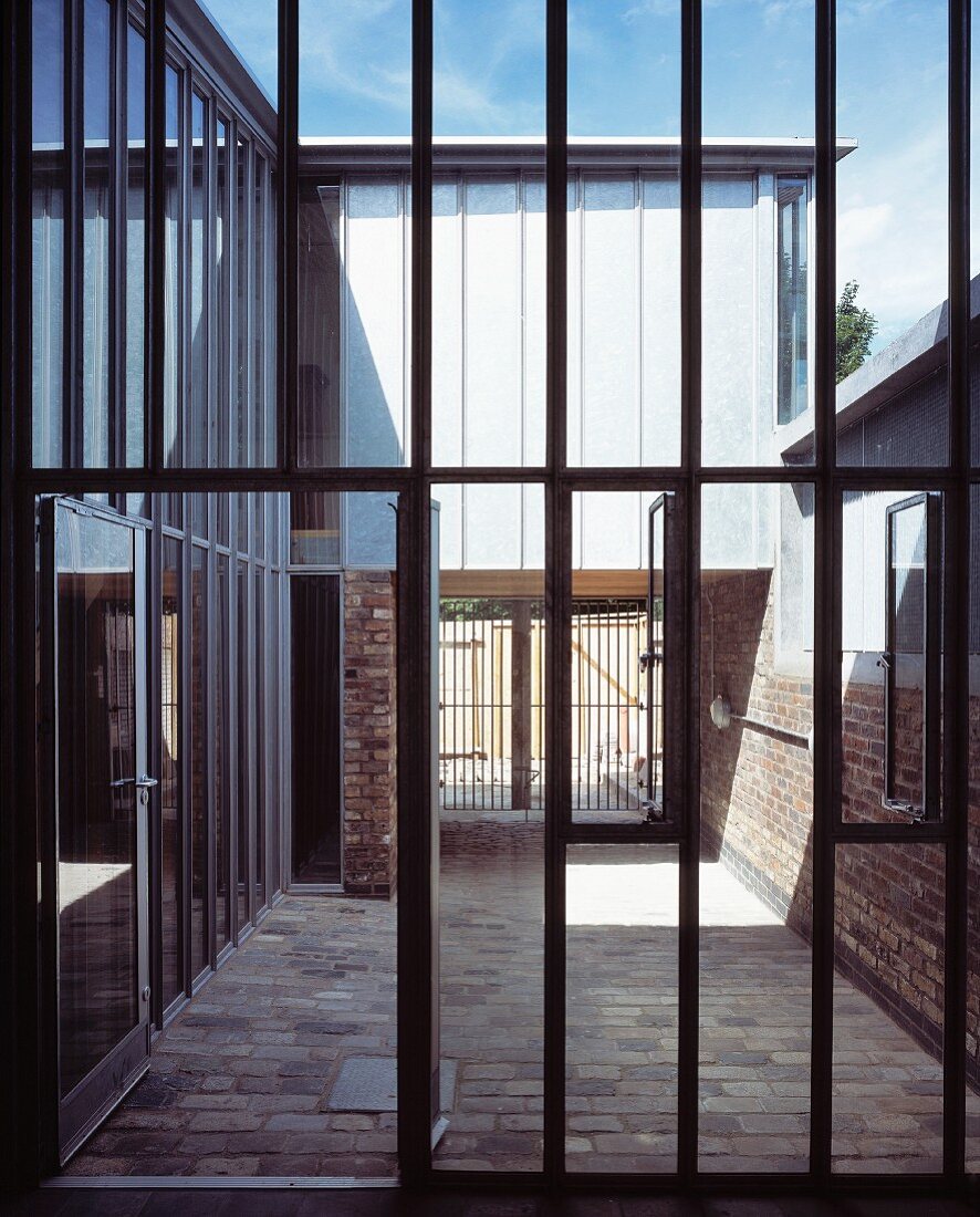 Steel and glass facade with open patio door and view of a courtyard