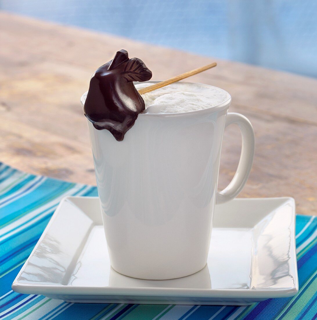 Steamed Milk in a White Mug with a Pear Shaped Chocolate Stick