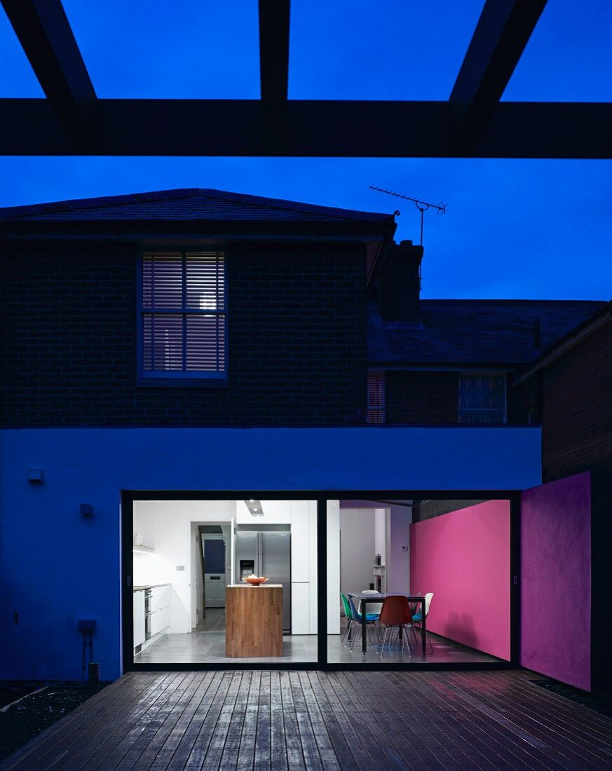 Zeitgenössisches Wohnhaus mit beleuchtetem Wohnraum in Abendstimmung