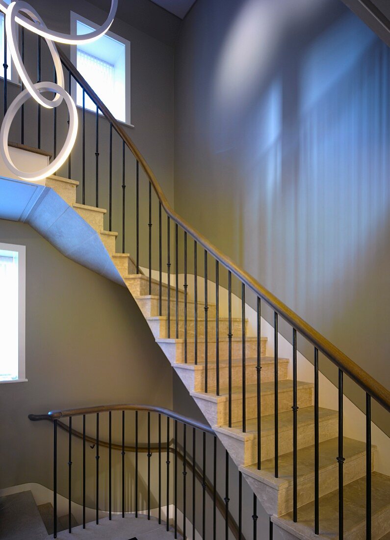 Curved stairs in a stairway with light coming in through a window