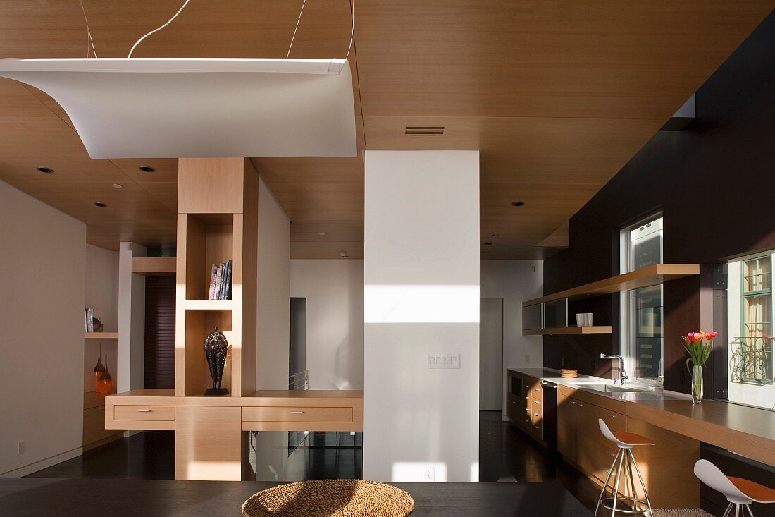 Contemporary, open-plan living room with breakfast bar and light canopy under a wooden ceiling