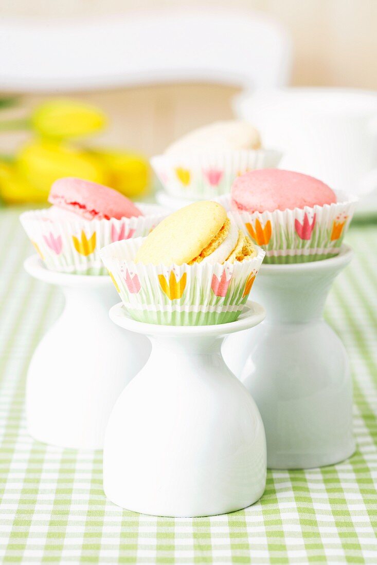 Macarons mit Trüffelcreme in Papierförmchen auf umgestülpten Eierbechern