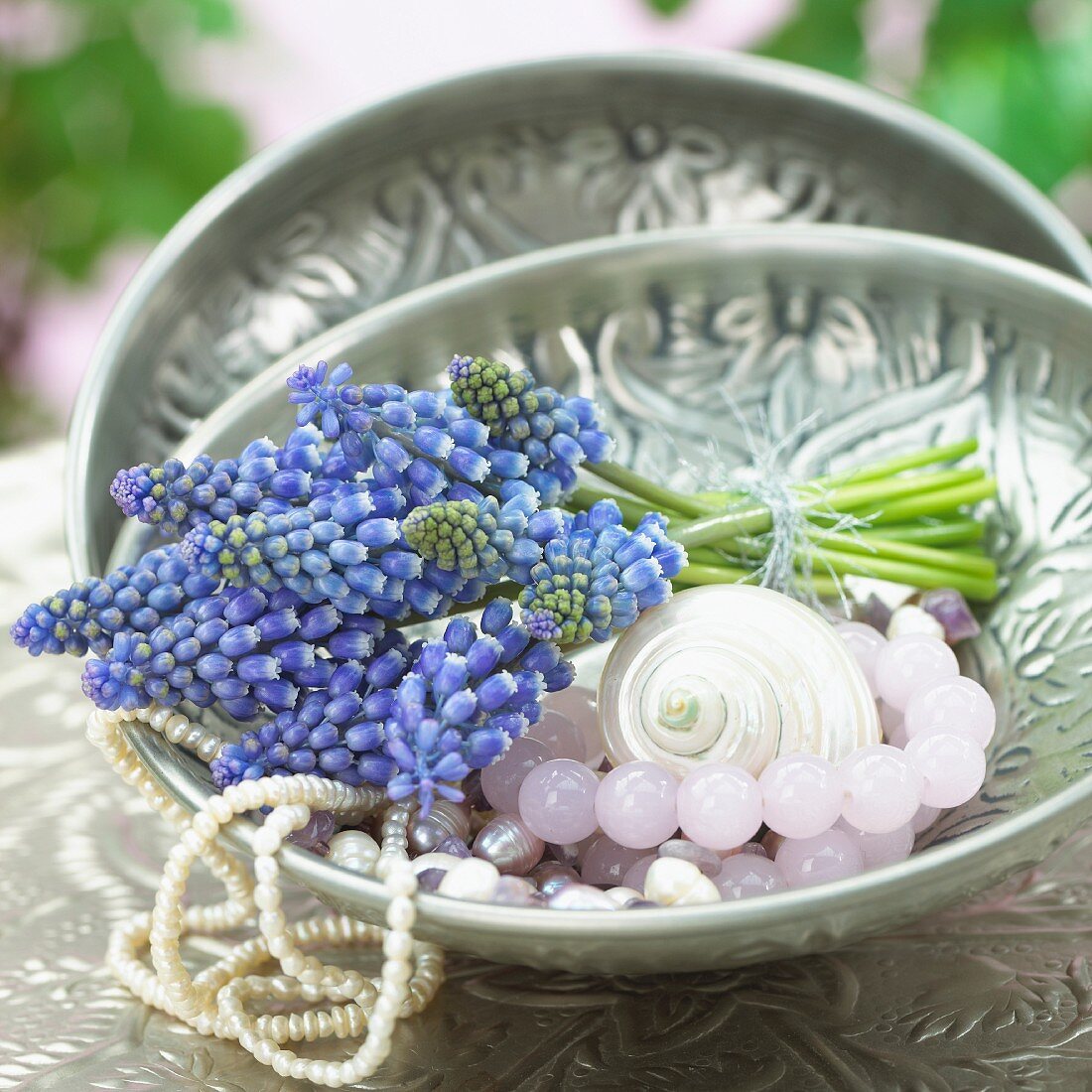 A bunch of grape hyacinths and jewellery in a bowl