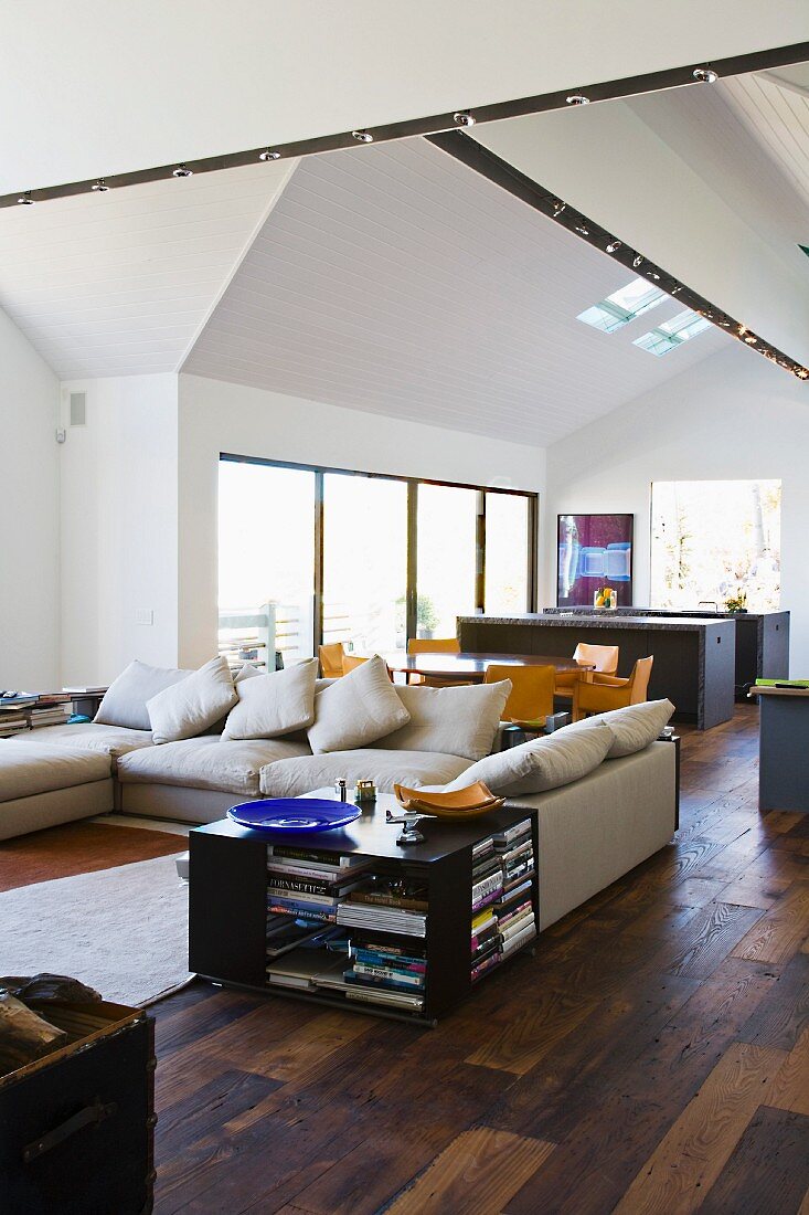 Open, modern living room with dark wood flooring and side table next to a living room suite