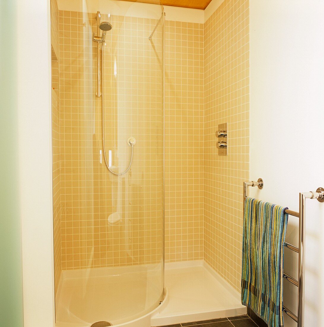 A semi-tiled shower cubicle with a curved wall and a stainless steel heated towel rail