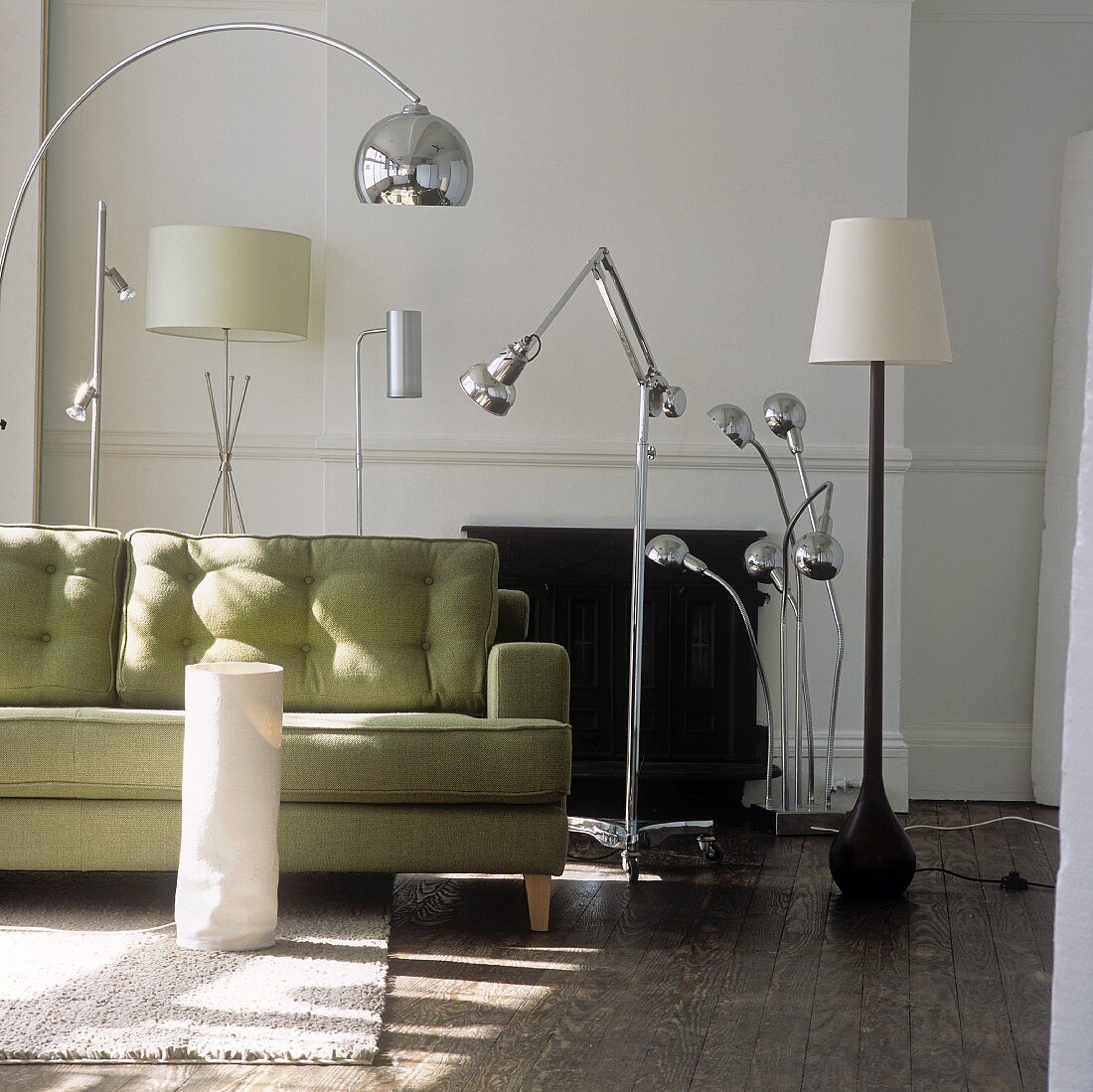A collection of floor lamps displaying a range of materials and style and a sofa in front of a fireplace