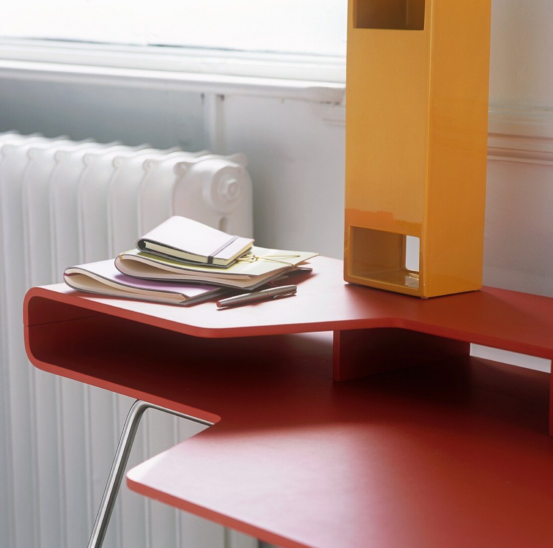 Roter Designer Schreibtisch und gelb lackierte Kiste mit Öffnungen