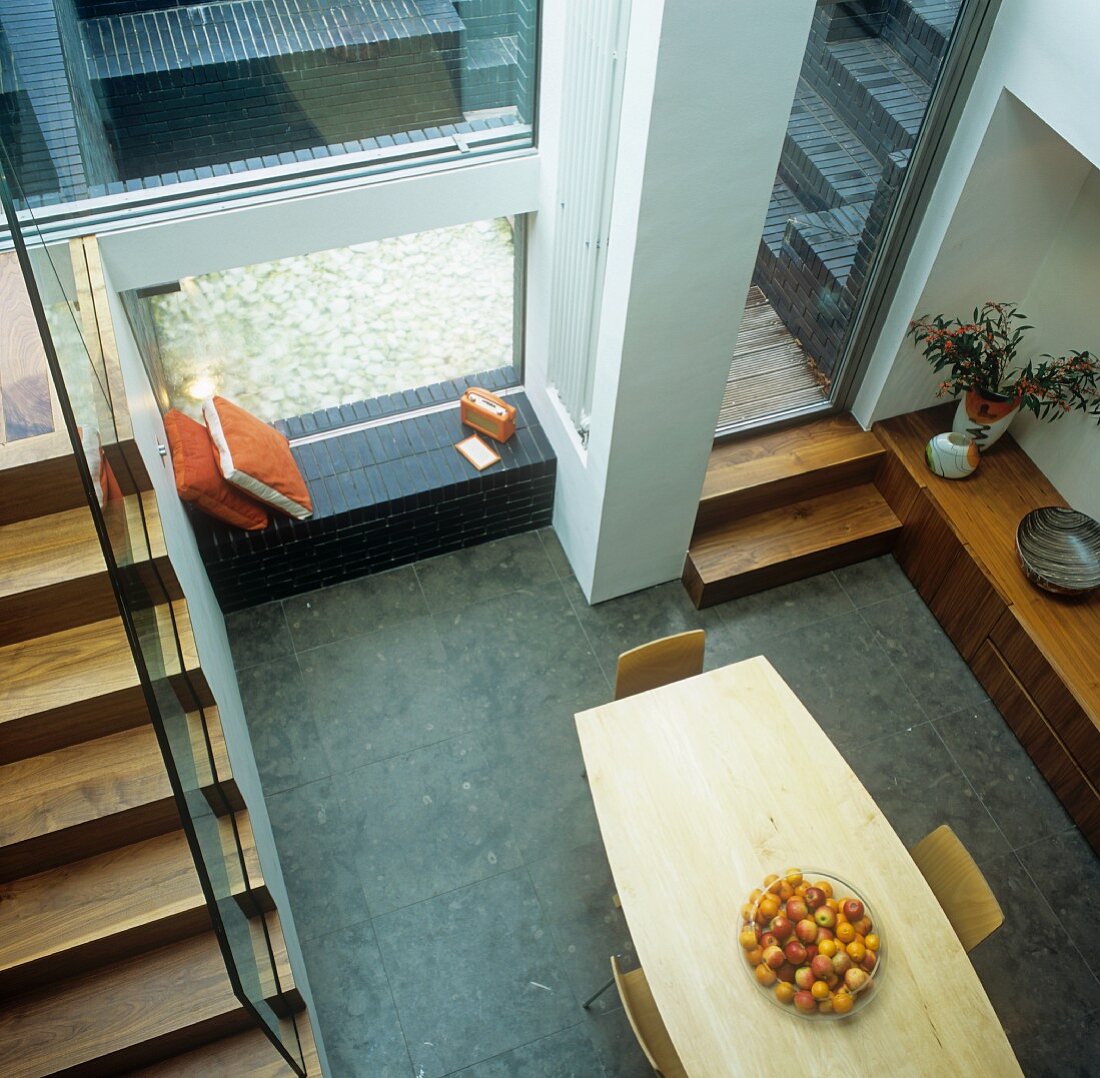 Moderner Esstisch aus Holz mit Obstschale neben Treppe im offenen Wohnraum