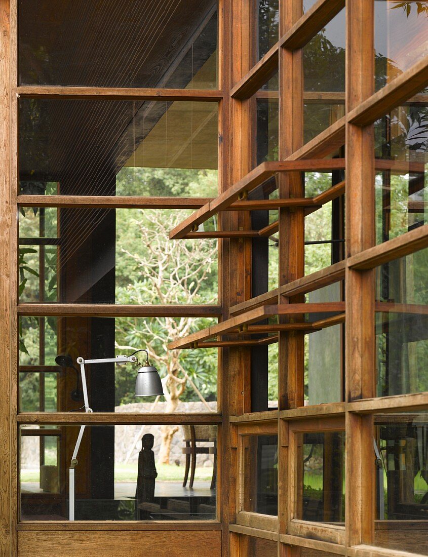 View of retro stainless steel lamp through traditional-style wood and glass facade with open windows