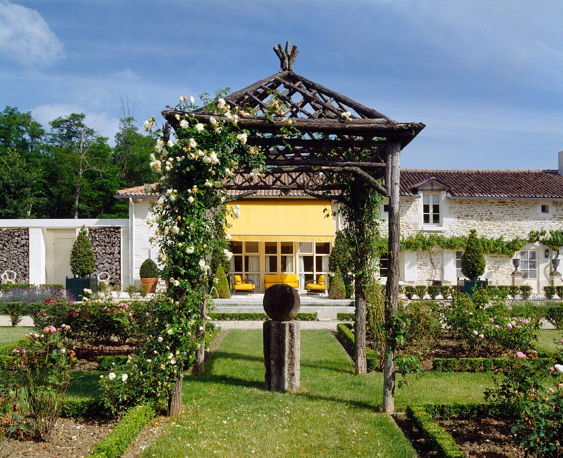 Pergola im rustikal asiatischen Stil im angelegten Garten vor Landhaus
