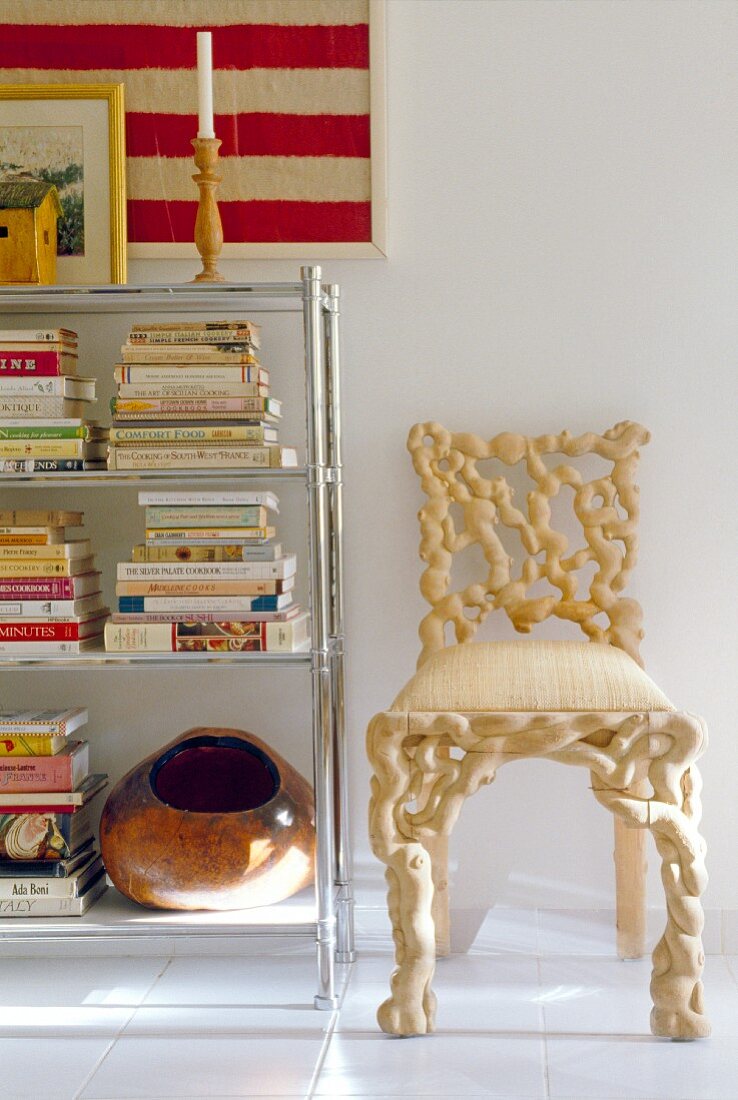 Chair of turned, light root wood next to a chrome bookcase