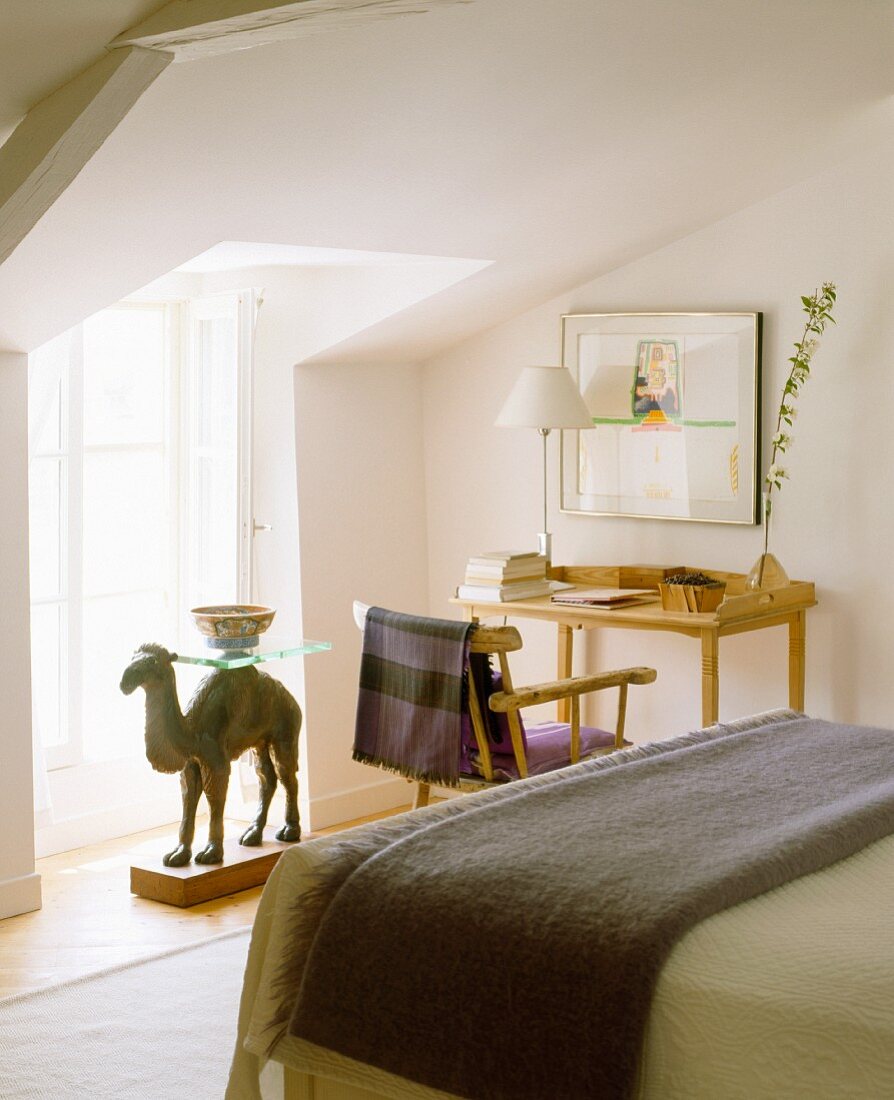 A bedroom with a simple study corner and a camel table in front of the windows