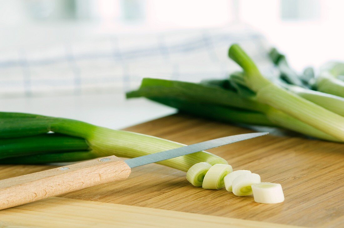 Spring onions being chopped on a wooden board