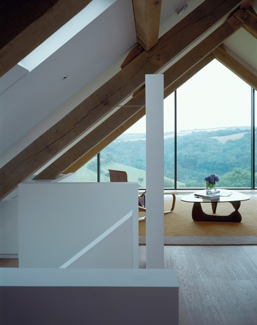 A converted attic room with a coffee table in front of a glazed gable with an impressive view
