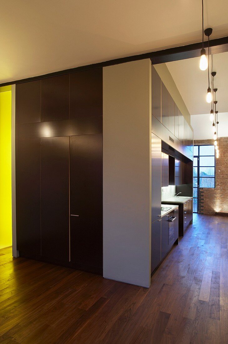 Central stairwell, bath and kitchen unit in London loft apartment with wall-to-wall wooden flooring