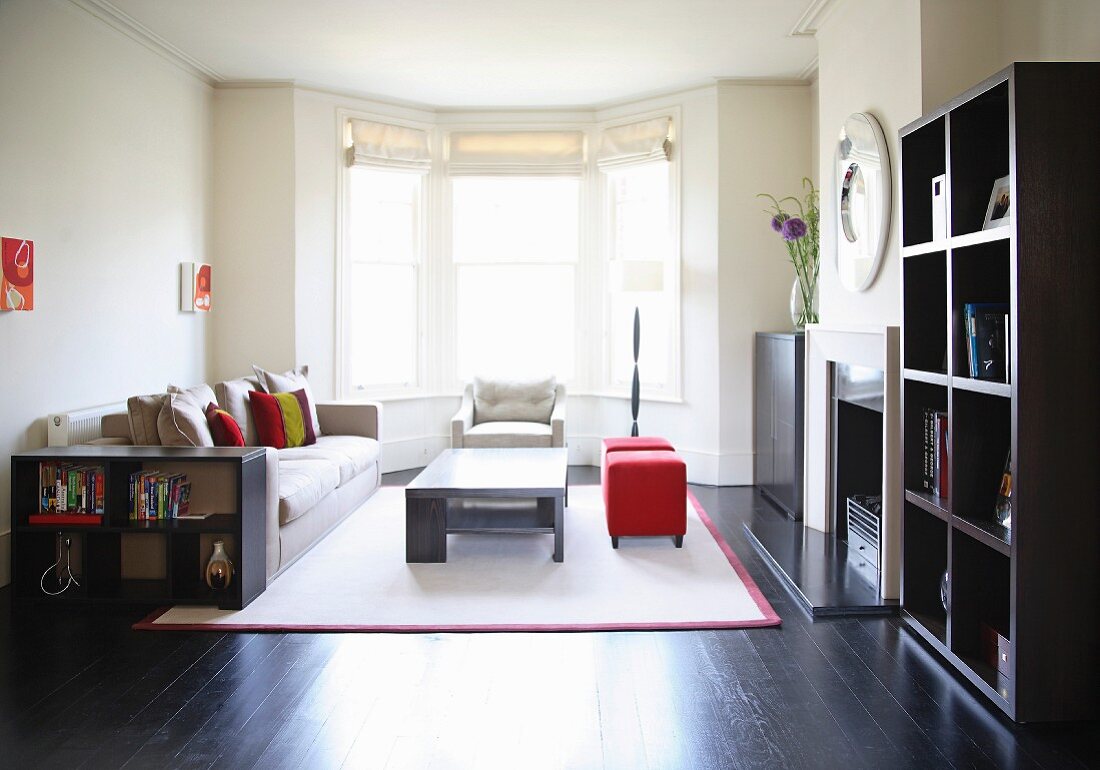 Comfortable seating on white rug in front of bay window in modern living room with black wooden floor