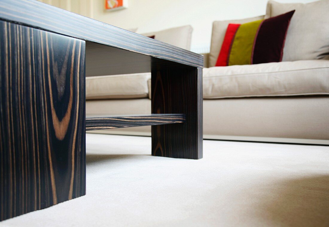 Coffee table in exotic wood and upholstered sofas with scatter cushions on a white rug