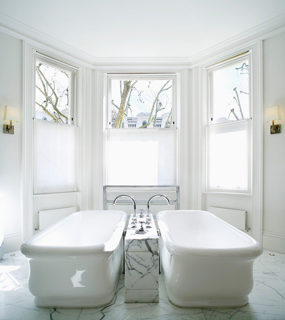 Vintage bathtubs with tap fittings in marble block in spacious, traditional bathroom with bay window