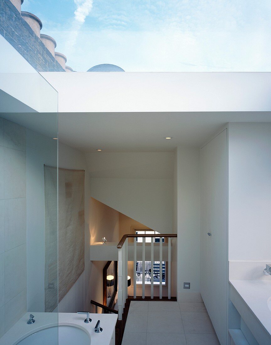 View from ensuite bathroom of bedroom below and of cloudy sky above through large skylight