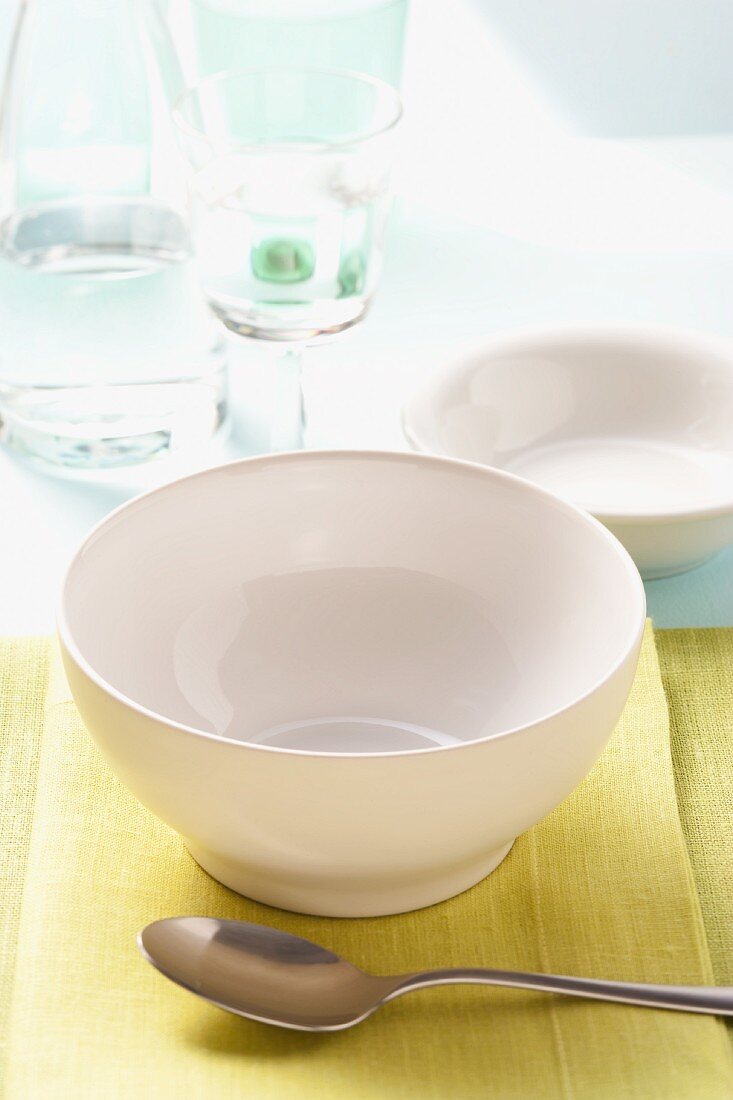 A simple place setting with a soup bowl, spoon and a glass of mineral water