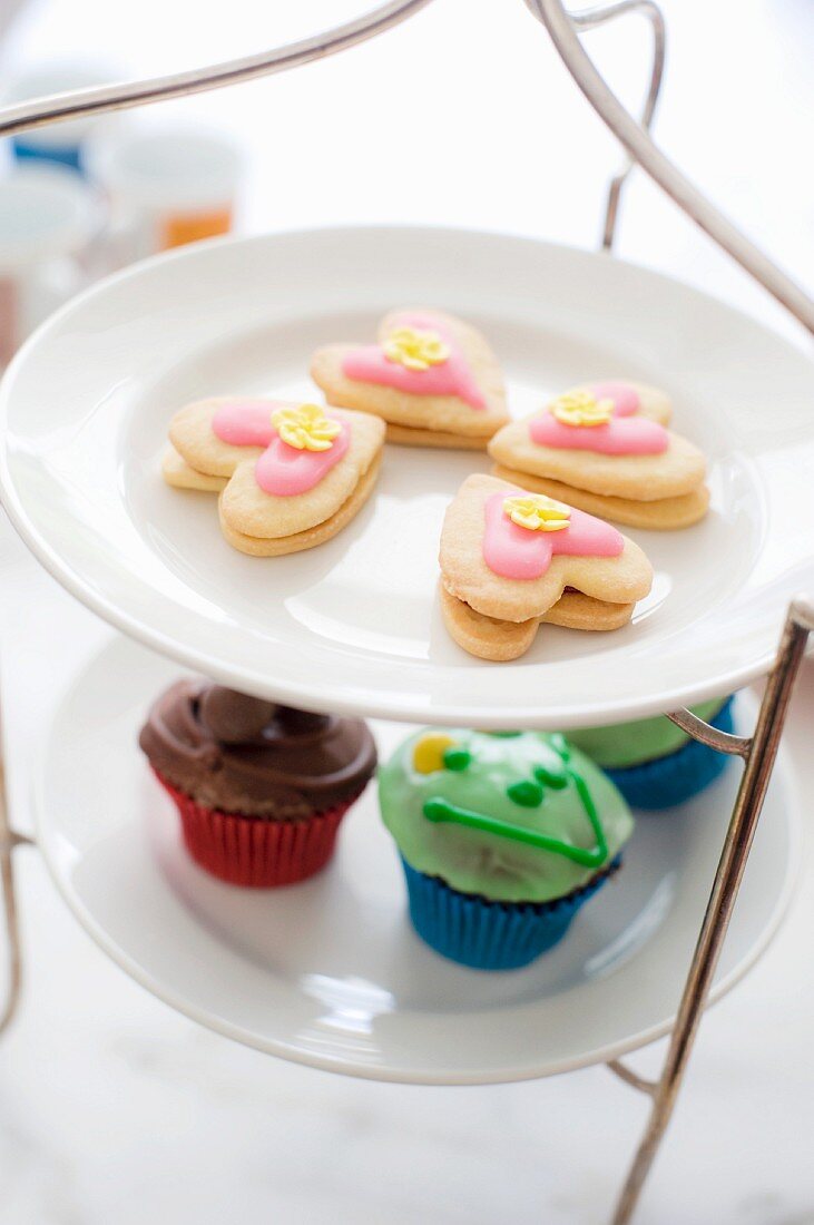 Etagere mit herzförmigen Plätzchen und Cupcakes