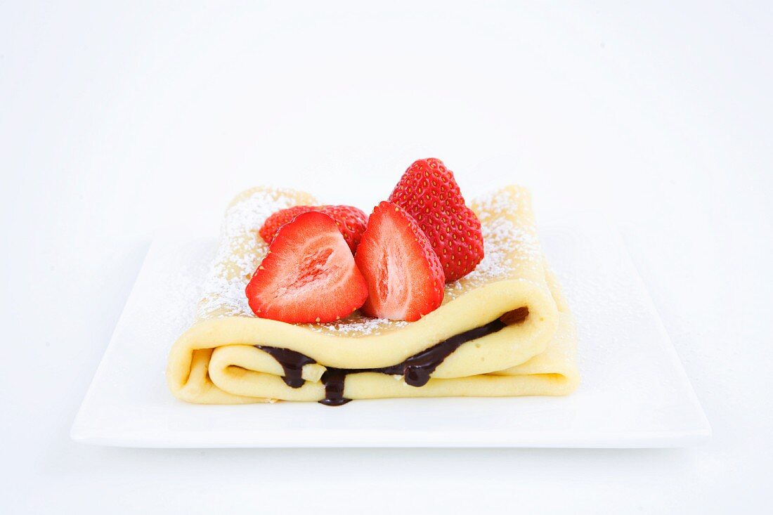 A pancake with chocolate sauce and fresh strawberries