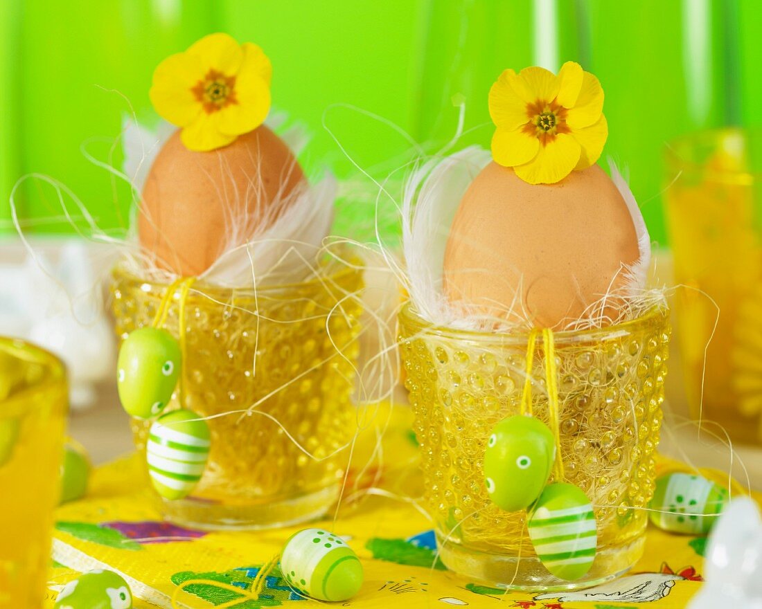 Egg cups decorated with flowers, feather and Easter eggs