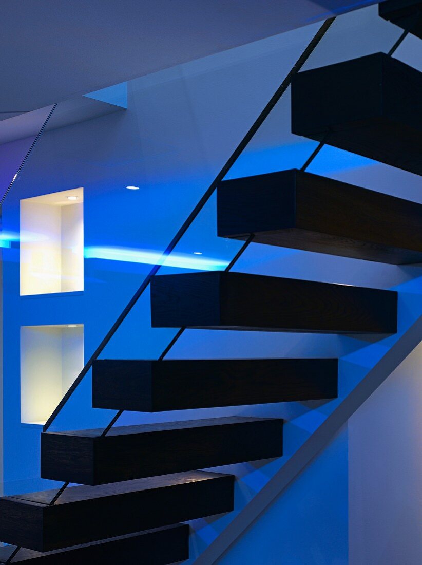 Contemporary stairs with floating wooden treads in low lighting