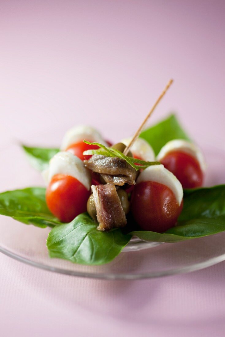 An appetiser consisting of sardines, olives, tomatoes and mozzarella
