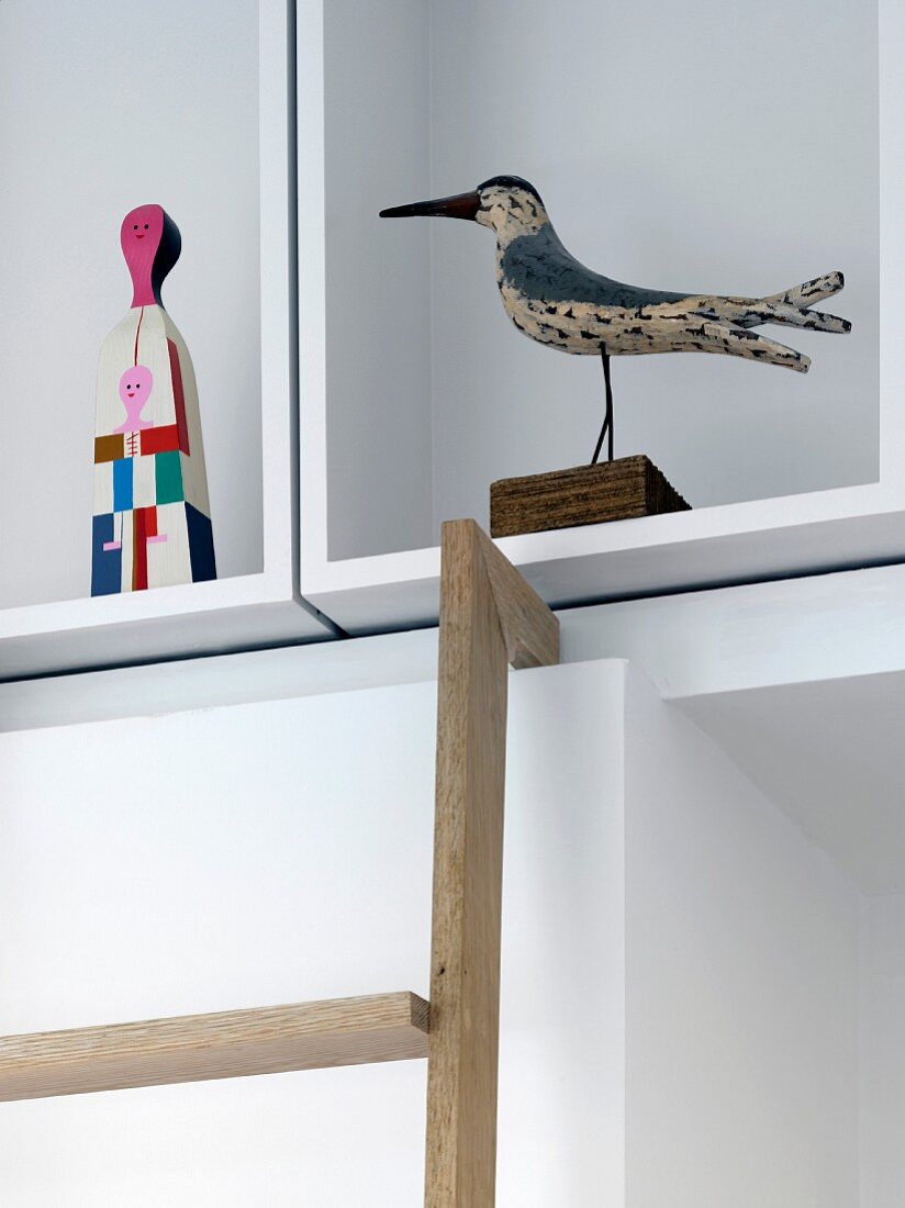 Bird figurine and modern painted figurine on white cubist shelving